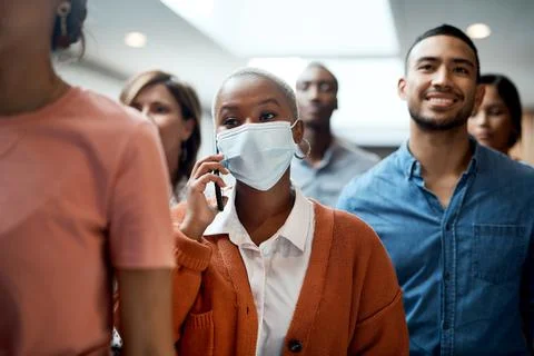 Have mask, will make it happen. a masked young businesswoman using a smartphone Stock Photos