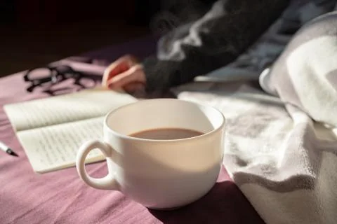Having coffee and reading in bed on lazy sunny morning.  Stock Photos