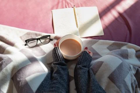 Having coffee and reading in bed on lazy sunny morning.  Stock Photos