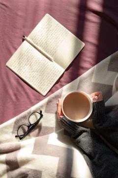 Having coffee and reading in bed on lazy sunny morning.  Stock Photos