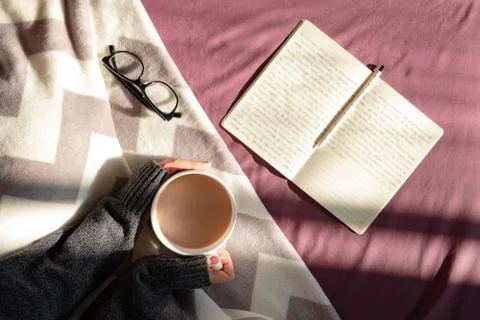 Having coffee and reading in bed on lazy sunny morning. Stock Photos