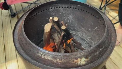 Having fire in metal smokeless drum burn barrel on DIY wooden deck in studio Stock Footage 327556783
