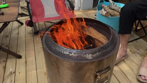 Having fire in metal smokeless drum burn barrel on DIY wooden deck in studio Stock Footage 327556790