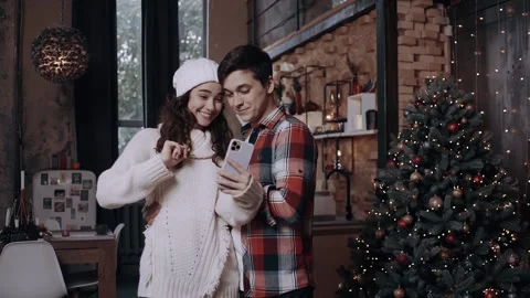 Having fun and taking pictures with their phone near the Christmas tree. Happy Stock-Footage 142942280