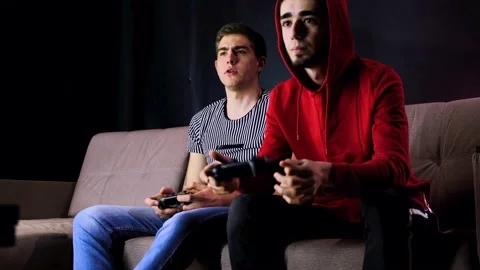 Having fun enjoy victory. Emotional two young guys are sitting on the couch in Stock Footage 134205089