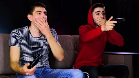 Having fun enjoy victory. Emotional two young guys are sitting on the couch in Stock Footage 134205251