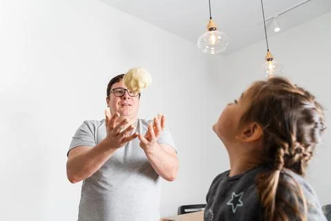 Having fun. Man in glasses throwing up dough while feeling playful with his Stock Photos