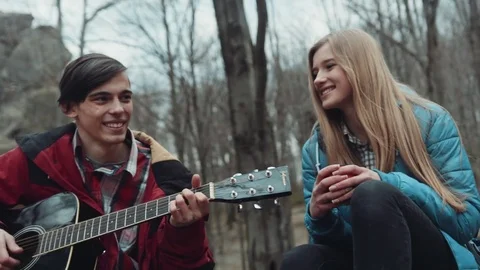 Having fun together, young musicians plays a song on the guitar to his beloved Stock Footage 73880370