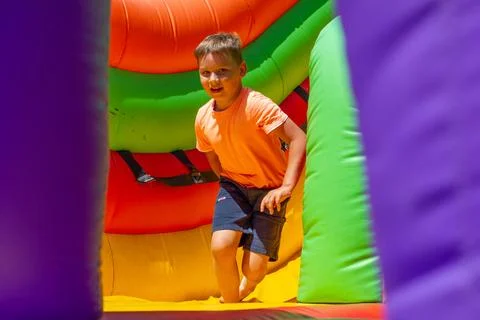 Having rolled down from an inflatable bright slide on a trampoline, the child Stock Photos