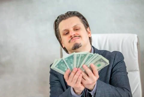 Having a smile on his face when looking at all the money in his hands Stock Photos