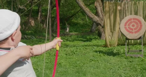Having taken aim, the child pulls the bowstring and shoots the arrow right at 動画素材 277681348
