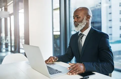 Having a technological advantage is key. a mature businessman working on his Stock Photos