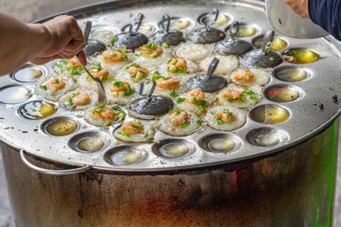 Hawker making tiny fried shrimp pancake- Banh Khot Vietnamese cuisine Stock Photos