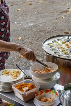 Hawker making tiny shrimp pancake at street food vendor market Stock Photos