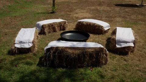 Hay Bale Seating With White Cushions Around Fire Pit Bowl On Grass Stock Footage 343893167