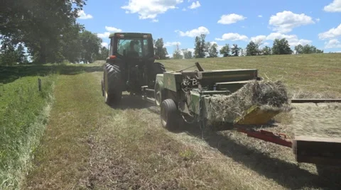 Haying square bales with a tractor and trailer. Stock Footage 61544962