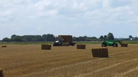 Haymaking process using a John Deere agricultural tractor and a New Holland.. Stock Footage 339907807