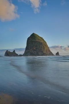 Haystack Rock with crashing waves at sunset, long distance shot. Stock Photos