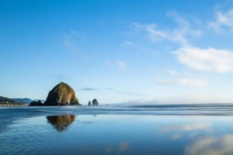 Haystack rock reflected in wet sand of ocean beach Stock Photos