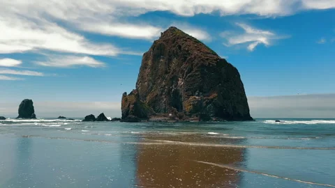Haystack Rock rising from Pacific Ocean near sandy beach, dramatic rock Stock Footage 308027412
