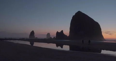 Haystack Rock sunset with tourists silhouette, Cannon Beach, Pacific Ocean - 4K Stock Footage 223763985