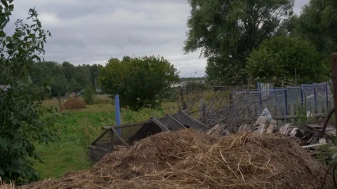 A haystack in some country-yard, a green meadow sorrounded by trees. Stock Footage 113885552