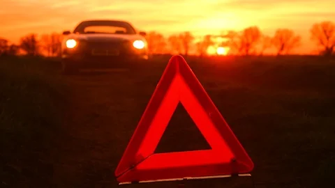 Hazard warning triangle by broken down car on country road at sunset uk Stock Footage 106182683