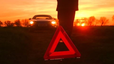 Hazard warning triangle by broken down car on country road at sunset uk Stock Footage 106184076