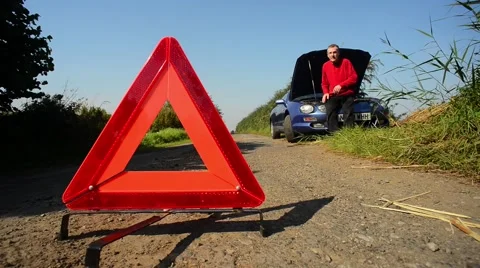 Hazard warning triangle by man with broken down car on country road uk Stock Footage 67530418