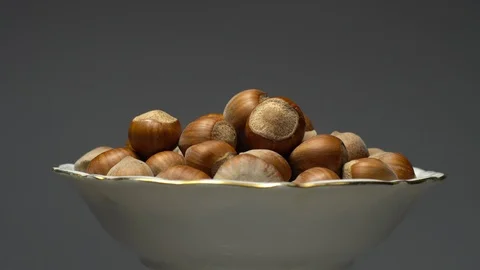 Hazel nuts in nutshell. Rotation. Closeup.  Walnuts in a bowl. Grey background. Stock Footage 101554405
