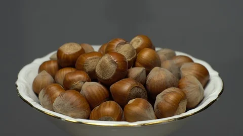 Hazel nuts in nutshell. Rotation. Closeup.  Walnuts in a bowl. Grey background. Stock Footage 101555635