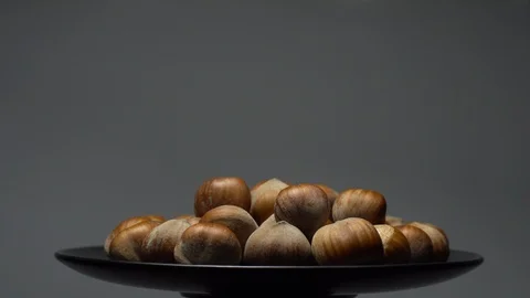 Hazel nuts in nutshell. Rotation. Closeup.  Walnuts in a bowl. Grey background. Stock Footage 101556084