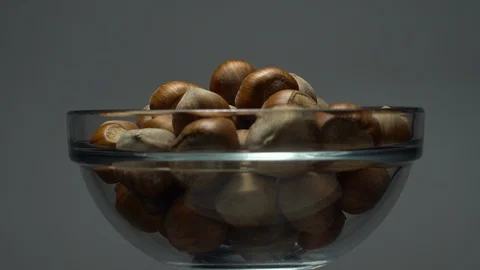 Hazel nuts in nutshell. Rotation. Closeup.  Walnuts in a bowl. Grey background. Stock Footage 101587679