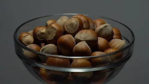 Hazel nuts in nutshell. Rotation. Closeup.  Walnuts in a bowl. Grey background. Stock Footage 101587804