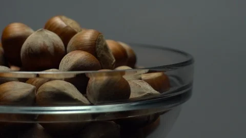 Hazel nuts in nutshell. Rotation. Closeup.  Walnuts in a bowl. Grey background. Stock Footage 101588397