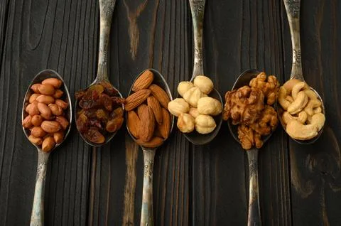 Hazelnut, cashews, raisins, almonds, peanuts, walnuts in silver spoons on a.. Stock Photos