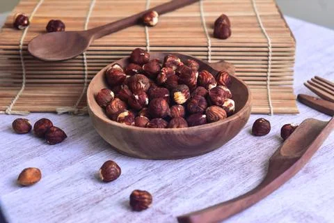 Hazelnut kernel inside wooden bowl on the side of sushi roller with wooden .. Stock Photos