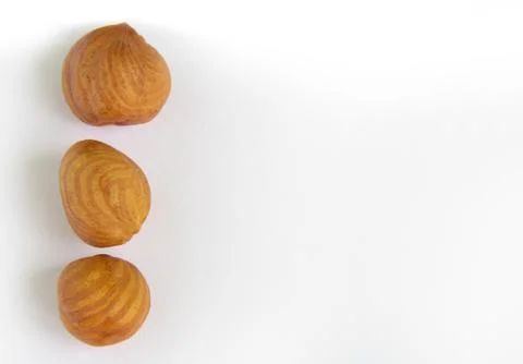 Hazelnut kernels. Three pieces close-up lie on a white background on the left Stock Photos