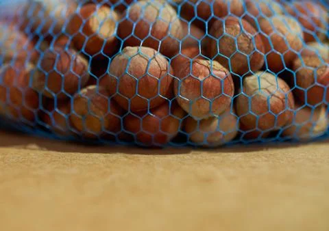 Hazelnuts in a blue packaging grid close up on a brown background Stock Photos