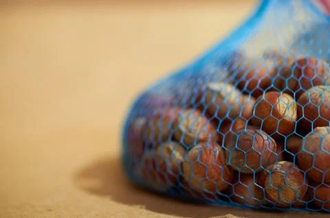 Hazelnuts in a blue packaging grid close up on a brown background Stock Photos