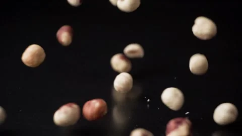 Hazelnuts fall on a black table, slow motion Video stock 189319205