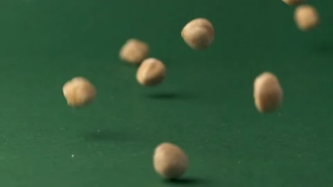 Hazelnuts falling down on the green background in a slow motion Stock Footage 229324760