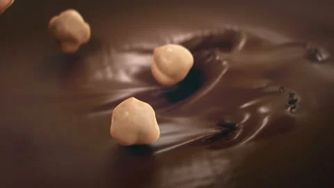 Hazelnuts Falling Into Liquid Chocolate in 4K Super slow motion Video stock 141678253