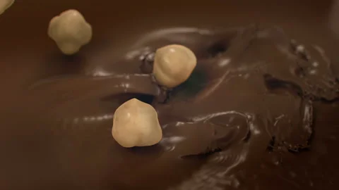 Hazelnuts Falling Into Liquid Chocolate in 4K Super slow motion Video stock 141678292