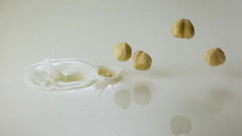Hazelnuts falling in milk and splashing Stock Footage 149433385
