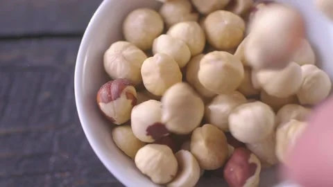 Hazelnuts falling into a white ceramic bowl on wooden table, slow motion 스톡 동영상 146073558