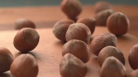 Hazelnuts falling onto wooden surface in super slow motion.  Shot on Phantom Stock Footage 117516257
