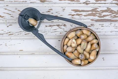 Hazelnuts with nutshells in a bowl and nutcracker on a wooden table Stock Photos