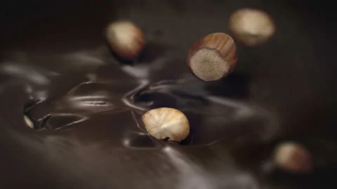 Hazelnuts Splashing Into Liquid Dark Chocolate in 4K Super slow motion Video stock 139144736