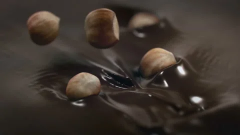 Hazelnuts Splashing Into Liquid Dark Chocolate in 4K Super slow motion Stock Footage 139144886